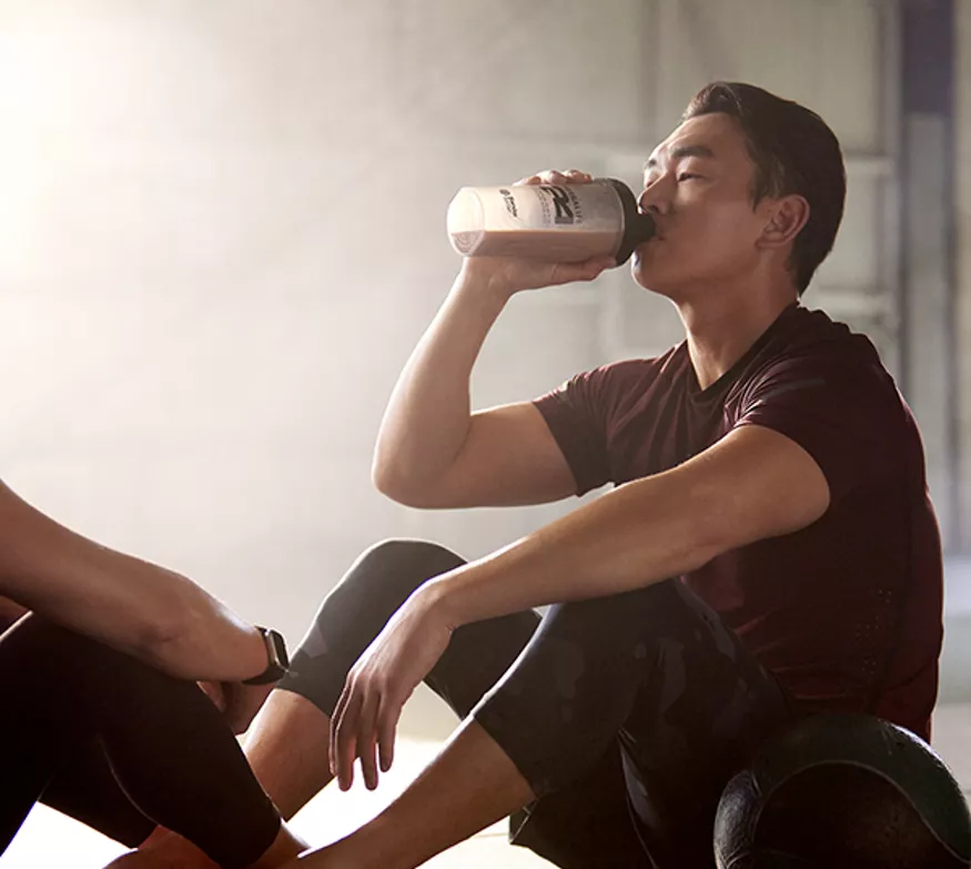 Mann drikker H24 Rebuild Strength på treningssenter